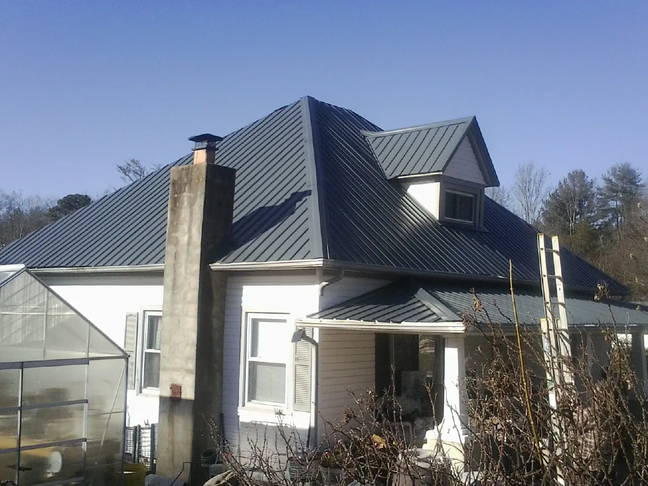 Dark blue standing seam metal roof on a white farmhouse with dormer — Slate & Tile Roof Repair by Roofing Brothers in Twin Peaks