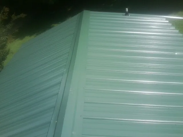 New green metal panels meeting at the ridge of a roof — Flat Roof Repair work by our crew in Twin Peaks