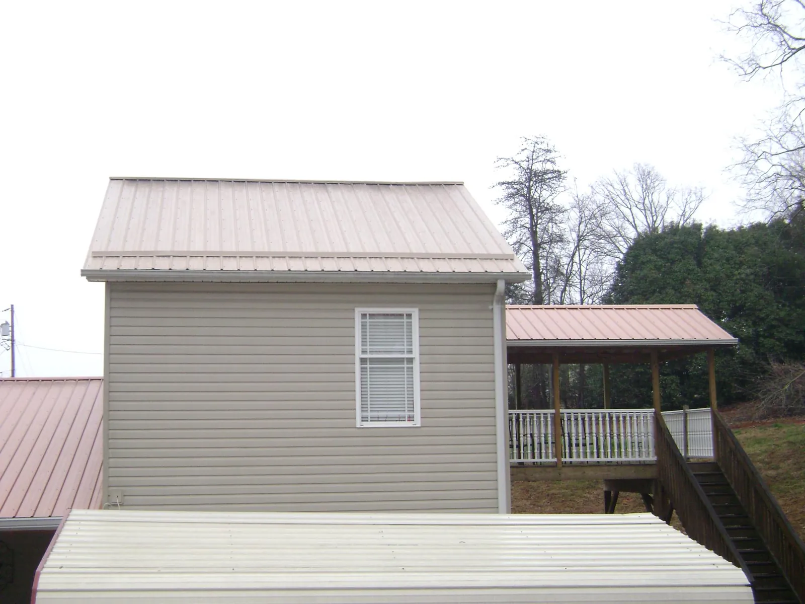 Tan metal roofs on a two story addition and attached porch, from a Roof Replacement job in Twin Peaks